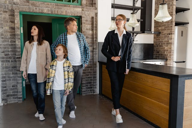 A real estate agent shows a family a modern kitchen. The family looks around curiously.